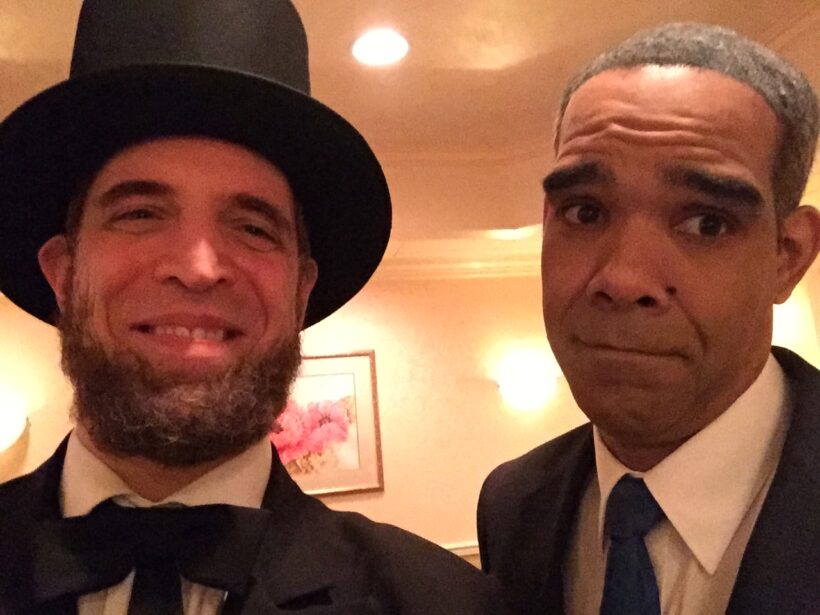 Two men dressed as historical figures smiling.