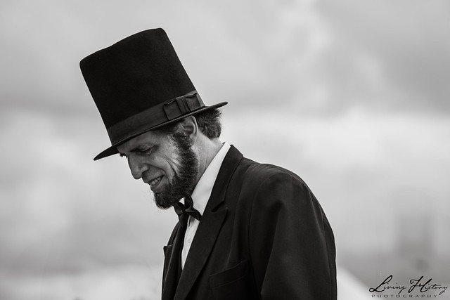 Man in top hat, historical attire, outdoors.